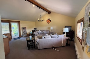 A living room with a sofa, a coffee table, a lamp, a bookshelf, and a fireplace. - Lighthouse Pointe Resort (Point Arena)