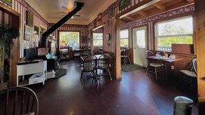 A restaurant with wooden walls, a staircase, and multiple tables and chairs. - Lighthouse Pointe Resort (Point Arena)
