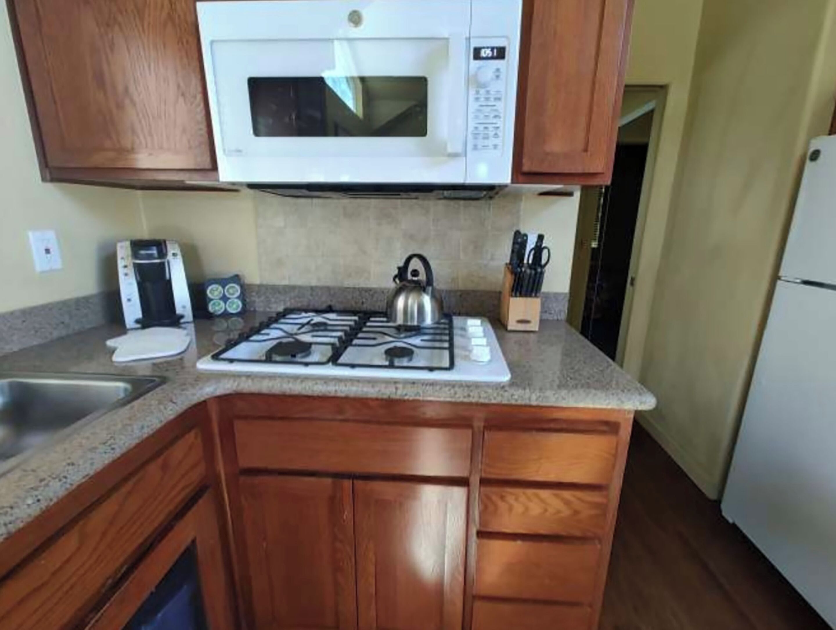 A compact kitchen with a microwave, gas stove, and a coffee maker.