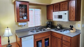 A kitchen with wooden cabinets, a built-in microwave, a gas stove, and a dishwasher. - Lighthouse Pointe Resort (Point Arena)