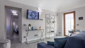 A modern living room with a grey sofa, a glass coffee table, and a TV mounted on the wall. - Entire floor: 8 beds (Vercelli)