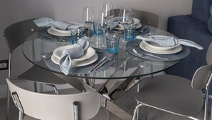A round glass dining table set with plates, glasses, and cutlery. - Entire floor: 8 beds (Vercelli)