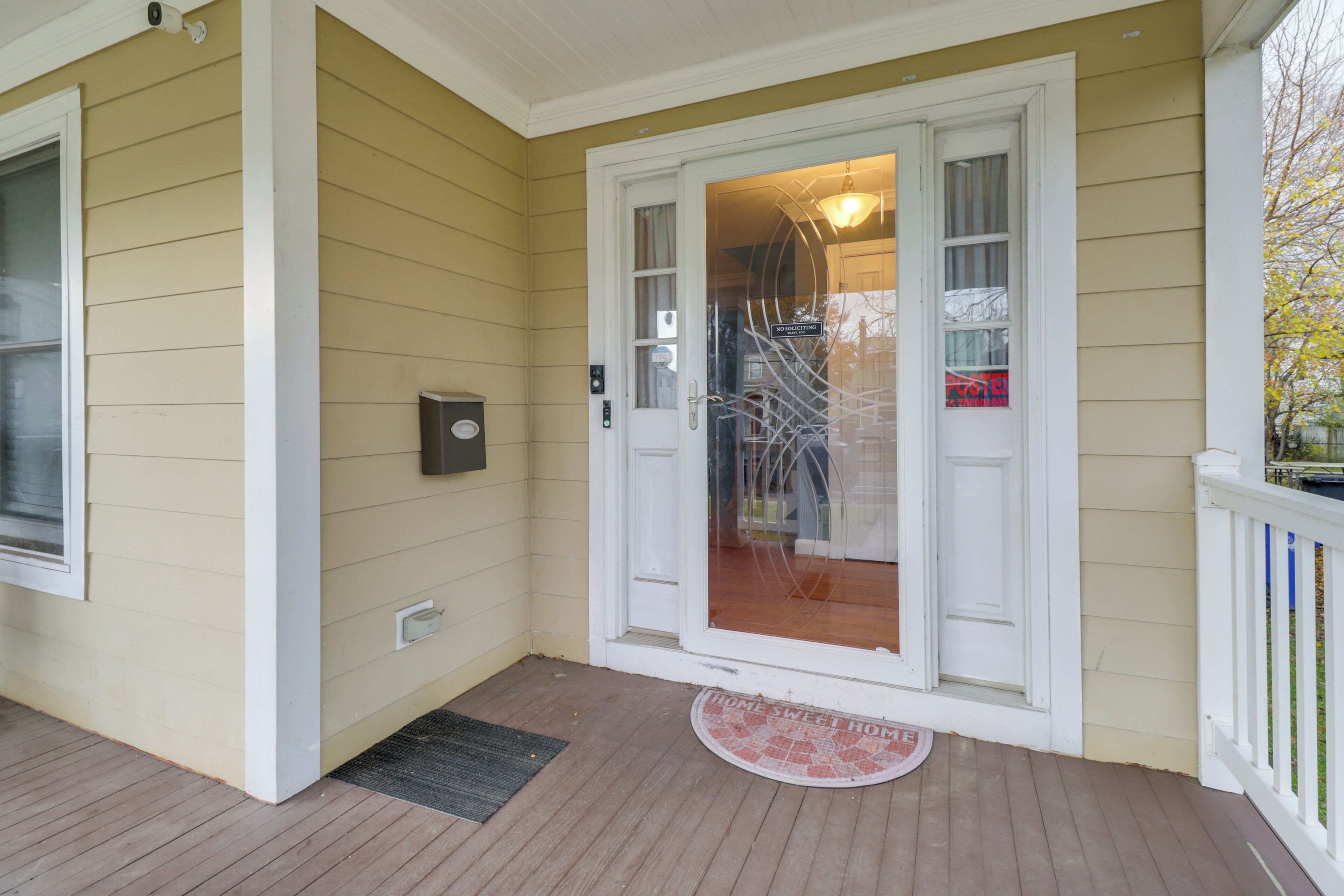 A house with a front porch, a door with glass panels, a mailbox, and a doormat.