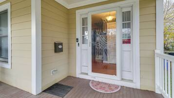 A house with a front porch, a door with glass panels, a mailbox, and a doormat.