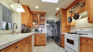 Una cocina con armarios de madera, un refrigerador de acero inoxidable, una estufa blanca y un microondas.