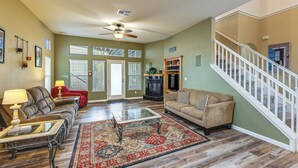A spacious living room with a red and beige color scheme, a glass coffee table, a fireplace, and a staircase with white railings. - Napa Nearby! Large Home w/ Hot Tub & Dtwn Access (Suisun City)
