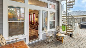 A covered patio with a dining area, a spiral staircase, and a view into the house. - Napa Nearby! Large Home w/ Hot Tub & Dtwn Access (Suisun City)