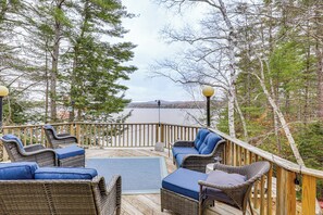 A wooden deck with wicker furniture and a view of a lake. - Lake Winnisquam Home: Fish, Hike & Explore! (Laconia)
