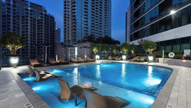 Una piscina con sillas de descanso y vistas a edificios altos al fondo.