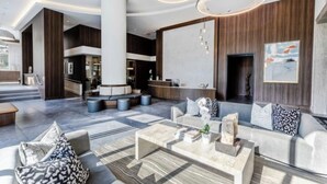 Un hall espacioso con diseño moderno, que cuenta con una zona de estar central, una mesa de recepción y un pilar grande.