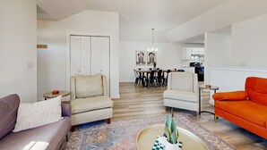 Ein Wohnzimmer mit Deckenventilator, ein Essbereich mit einer Kristallleuchter und eine Küche im Hintergrund.