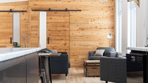 Un salon moderne avec un mur en bois, un canapé, une table basse et un coin repas comprenant une table et des chaises.