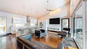 Un espacio habitable moderno con cocina, zona de estar y ventanas amplias.