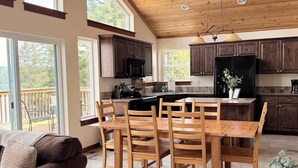 A spacious kitchen with wooden cabinets, a dining table with chairs, and a view of the outdoors. - Unwind at Lakeside Hideaway overlooking CDA Lake (Harrison)