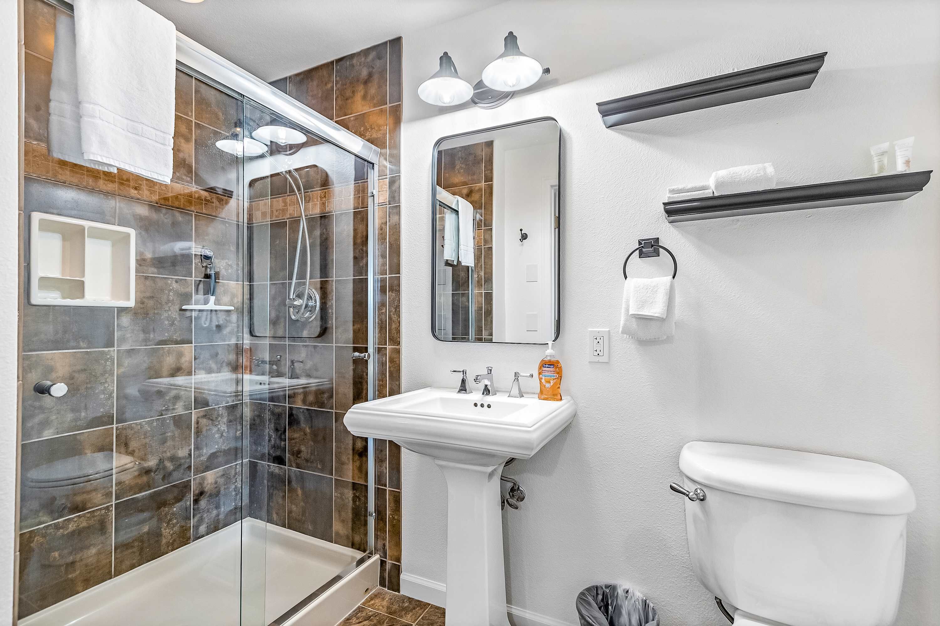 A modern bathroom with a glass shower enclosure, a white sink, and a toilet.