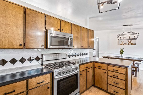 A modern kitchen with wooden cabinets, a stainless steel stove, and a microwave.
