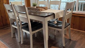 A dining table with six chairs, a woven placemat, and a small plant.