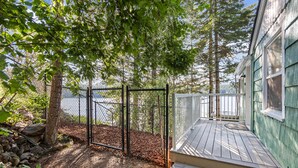A wooden deck with a railing, a fenced area, and a view of a body of water.