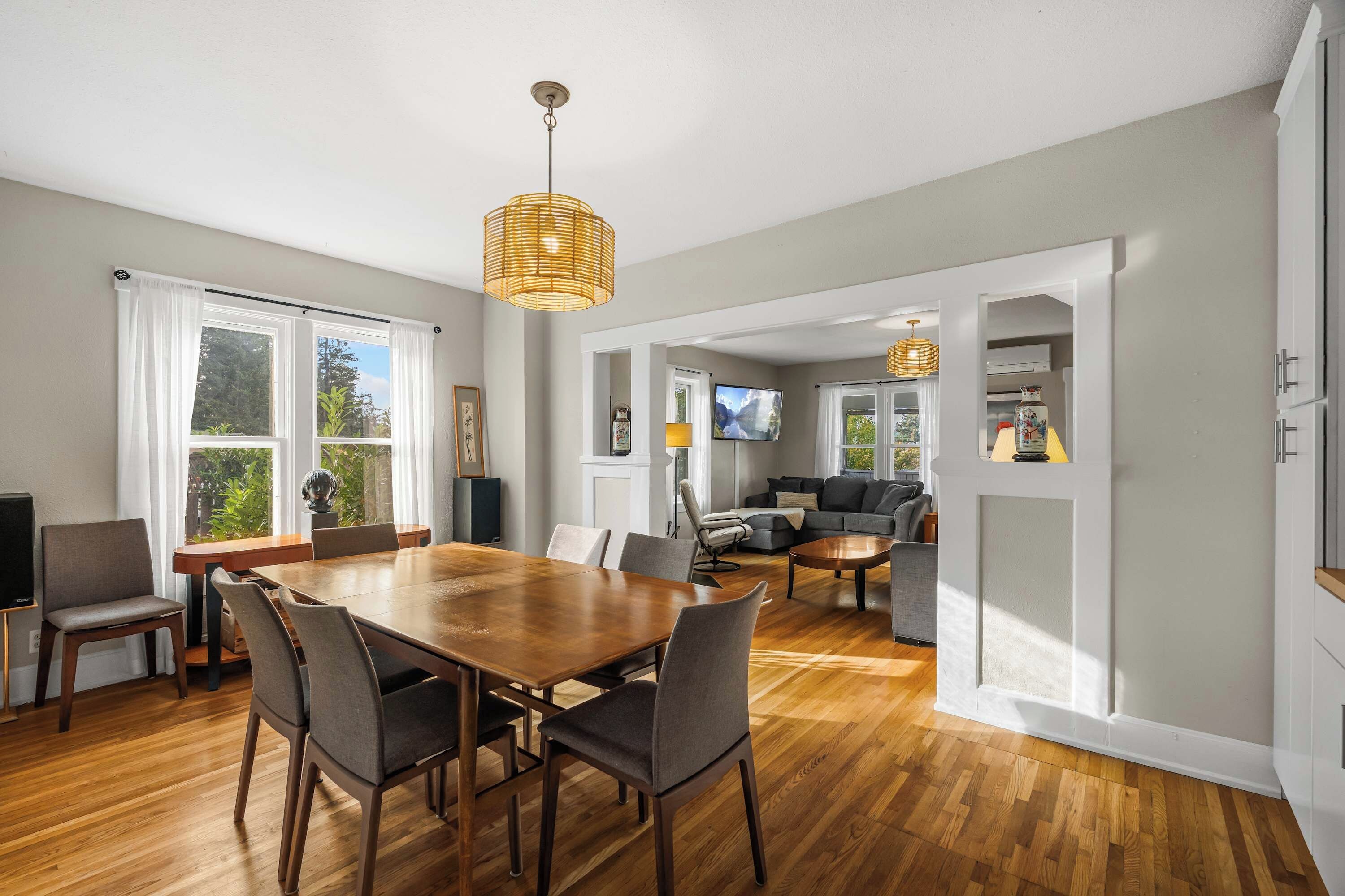 A spacious living area with a wooden dining table, comfortable seating, and a television.