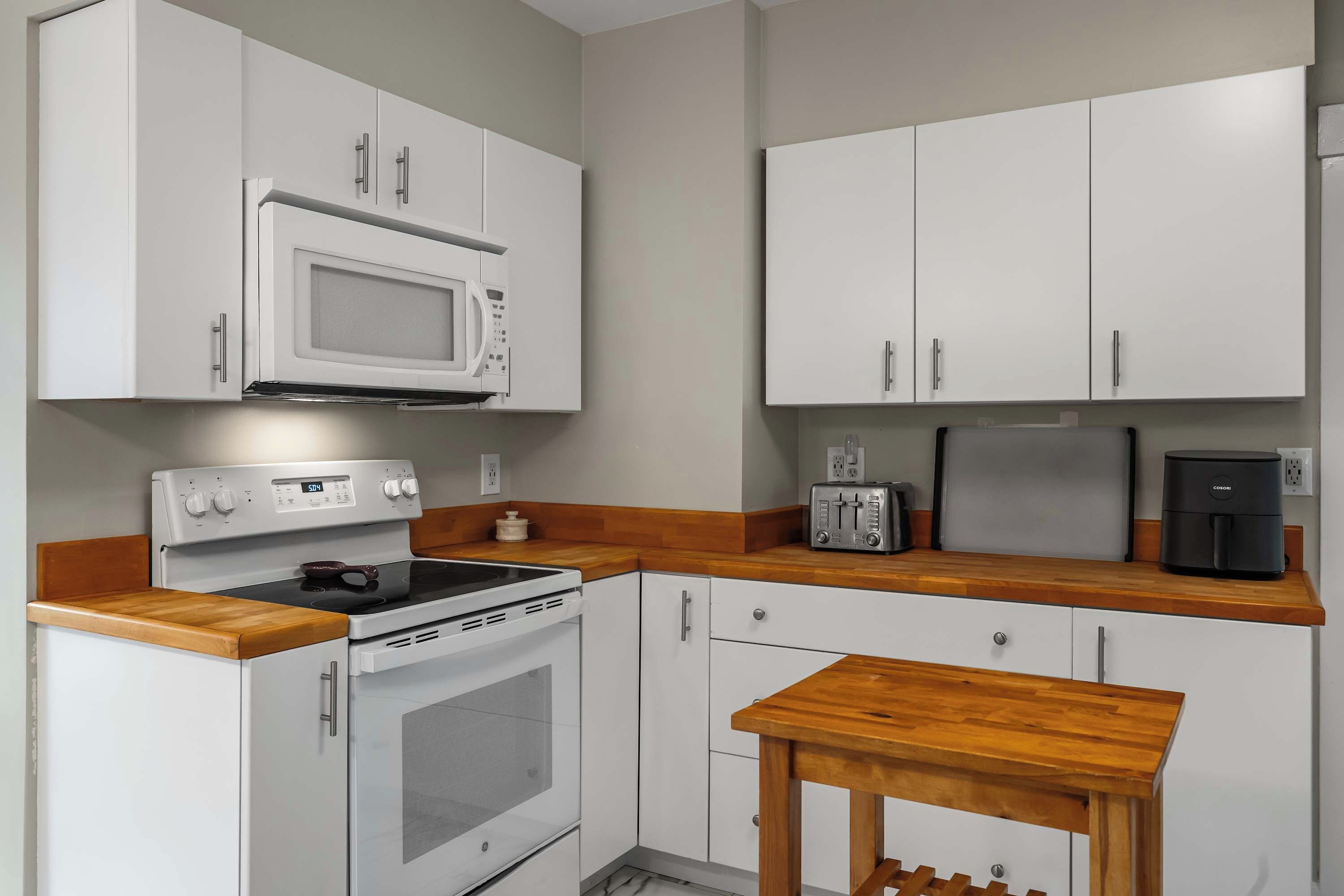 A compact kitchen with white cabinets, a microwave, a toaster, and a coffee maker.