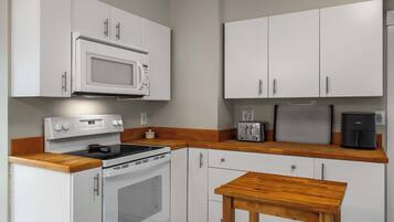 A compact kitchen with white cabinets, a microwave, a toaster, and a coffee maker.
