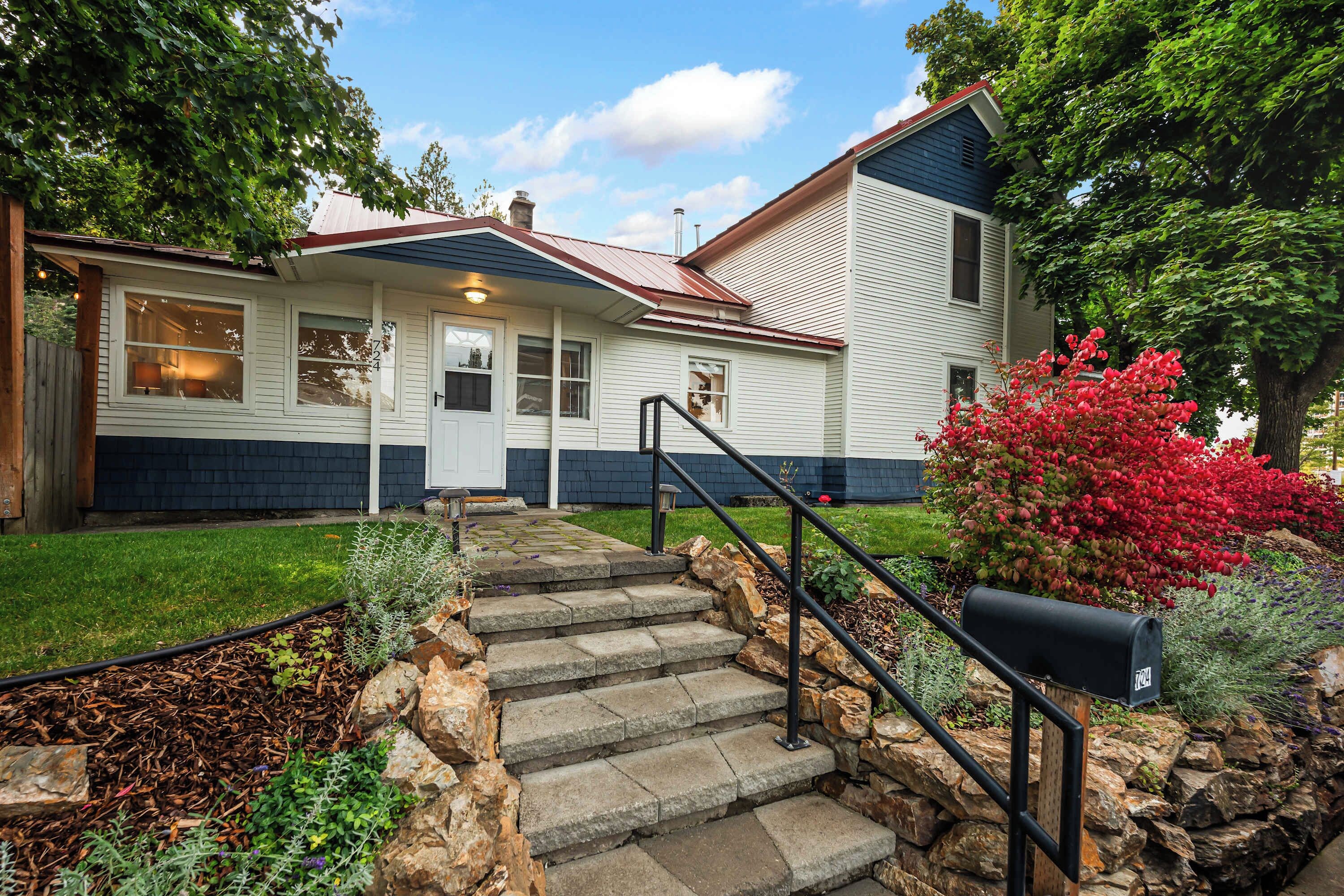 A two-story house with a front porch, stone steps, and a mailbox.