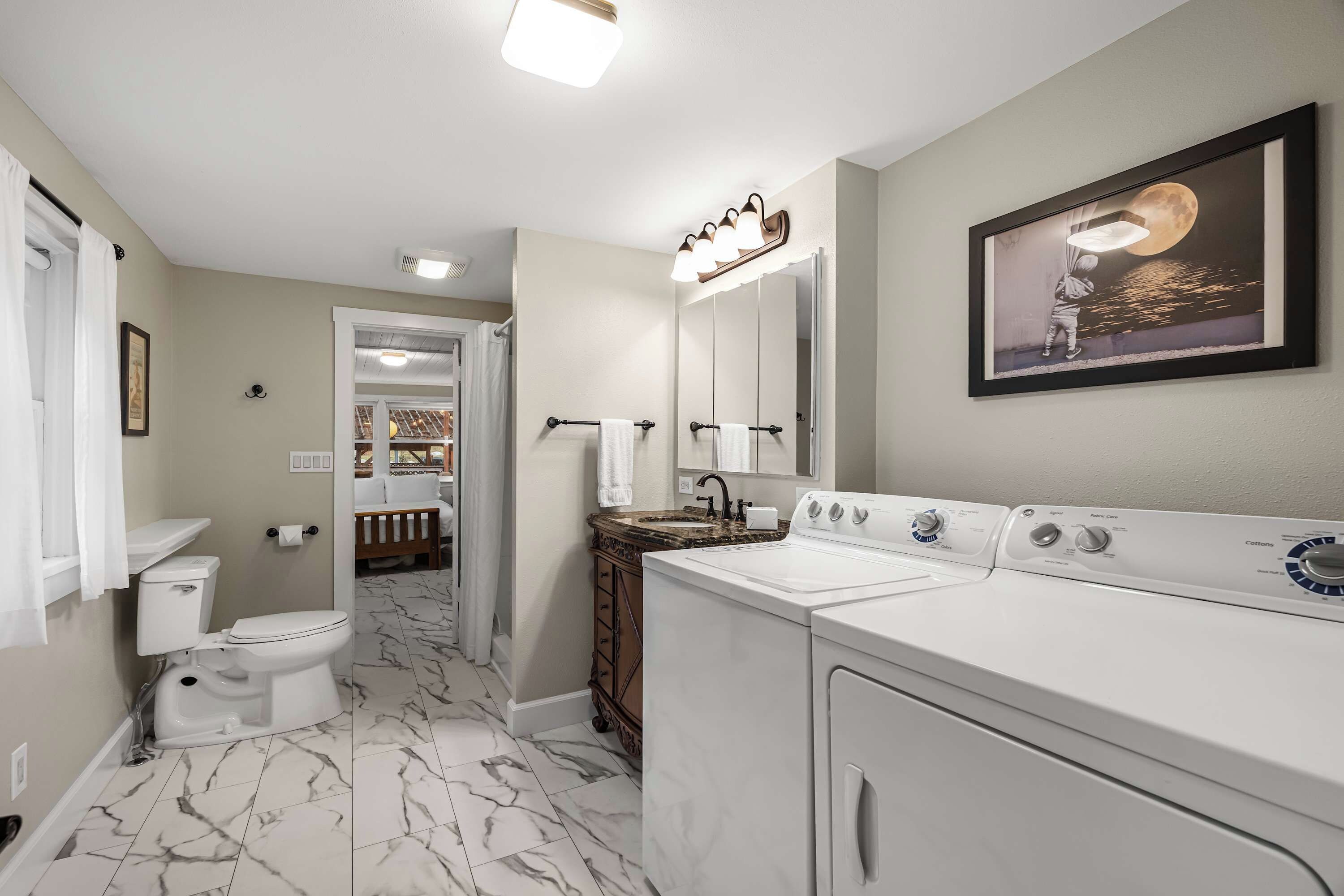 A bathroom with a toilet, sink, vanity, and a washing machine.
