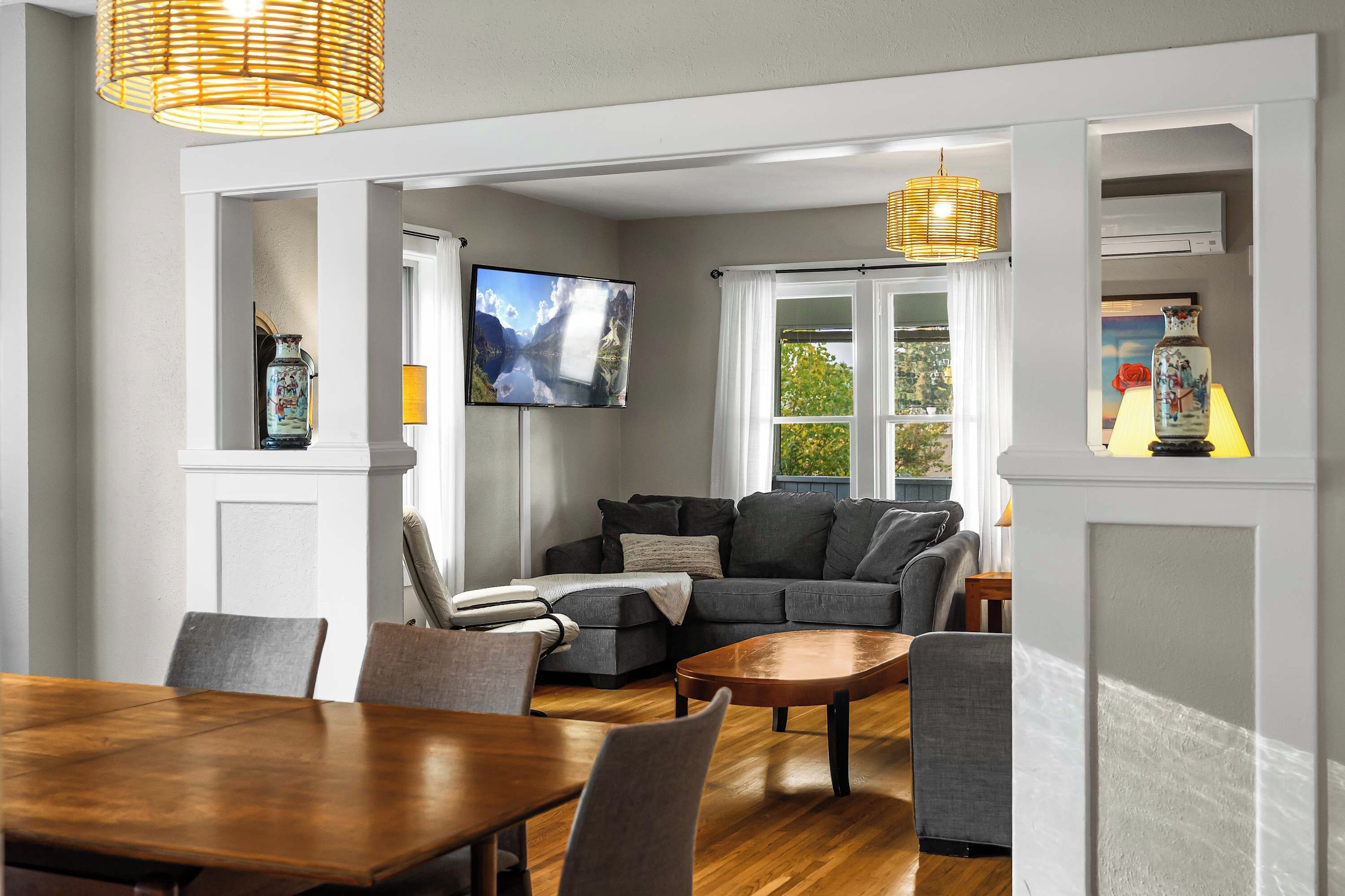 A modern living room with a grey sofa, a wooden coffee table, and a television mounted on the wall.