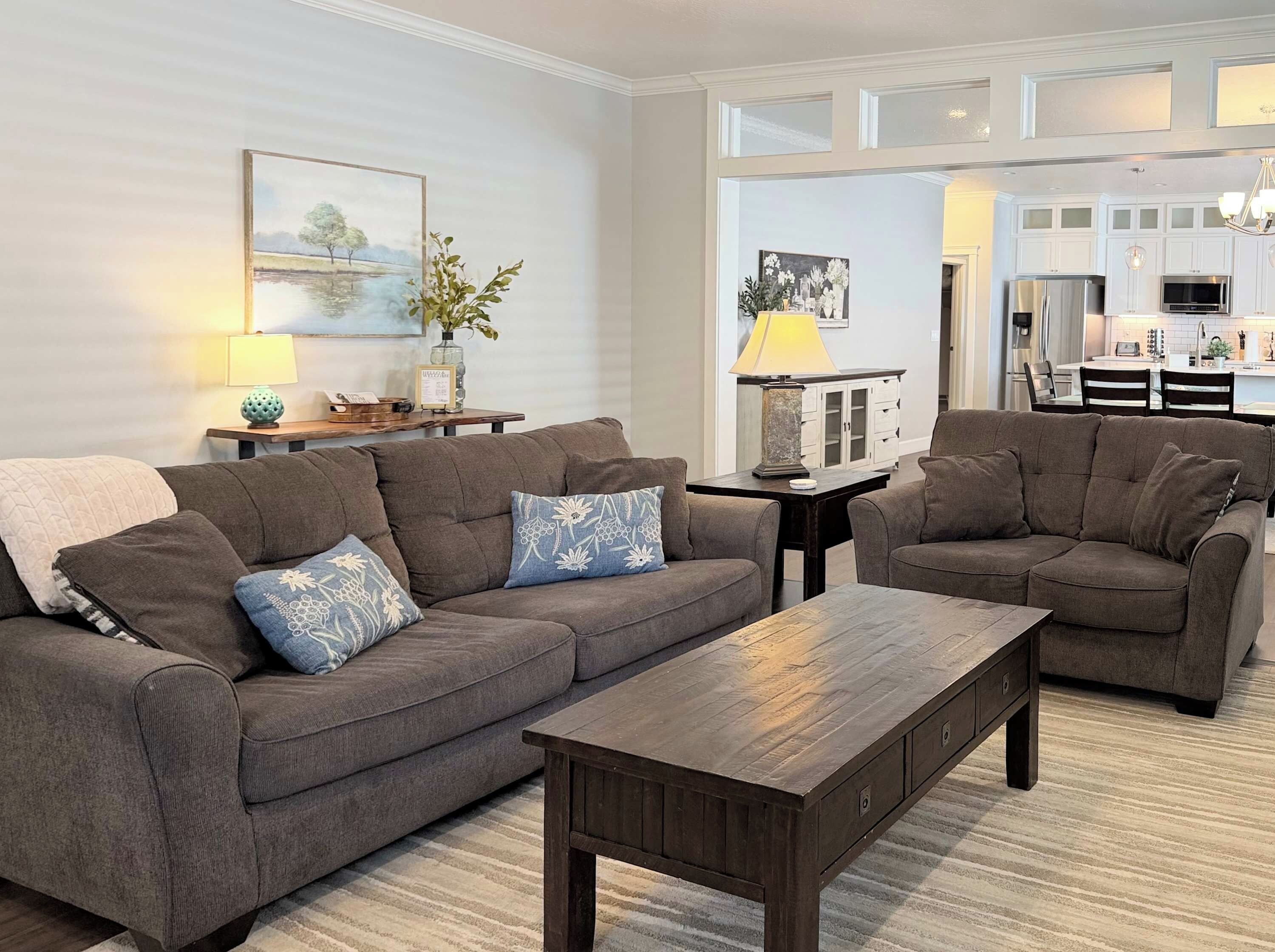 A living room with two sofas, a coffee table, and a dining area with a chandelier.
