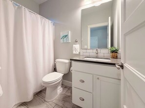 Een badkamer met toilet, wastafel, spiegel en douchegordijn.