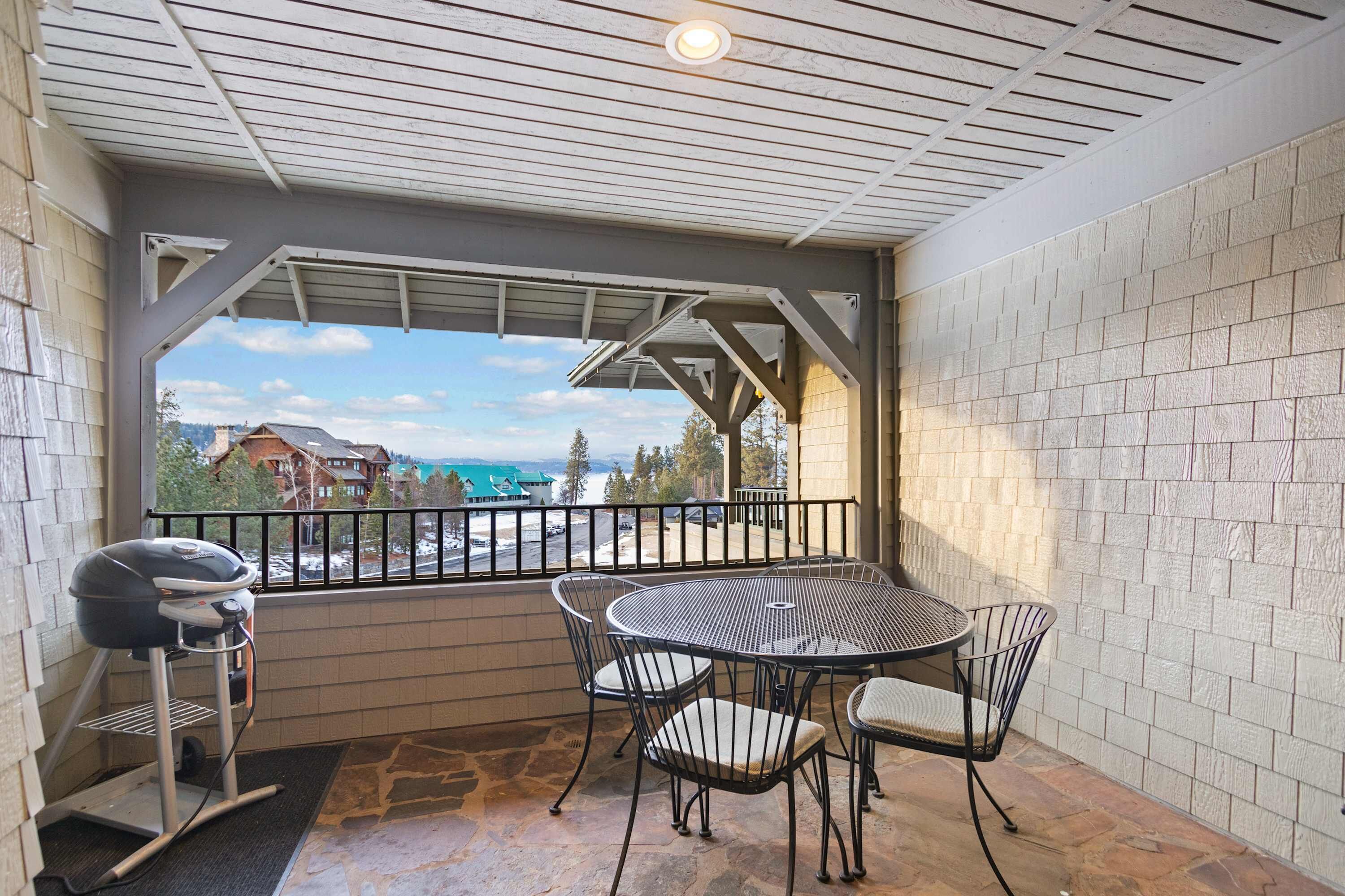 A covered patio with a grill, a round table, and four chairs.