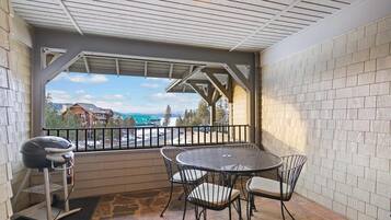A covered patio with a grill, a round table, and four chairs.