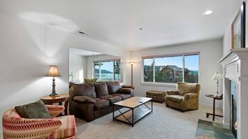 A living room with a brown leather sofa, a patterned armchair, a wooden coffee table, and a fireplace.