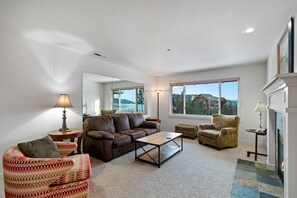 A living room with a brown leather sofa, a patterned armchair, a wooden coffee table, and a fireplace.
