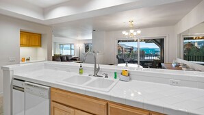 A modern kitchen with a large island, double sink, and a view of the balcony. - Unwind at Marina's Edge near Gozzer (Harrison)