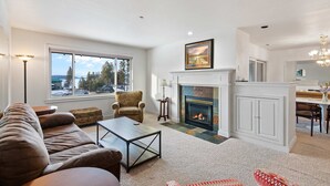 A spacious living room with a fireplace, a sofa, a coffee table, and a view of the outdoors. - Unwind at Marina's Edge near Gozzer (Harrison)