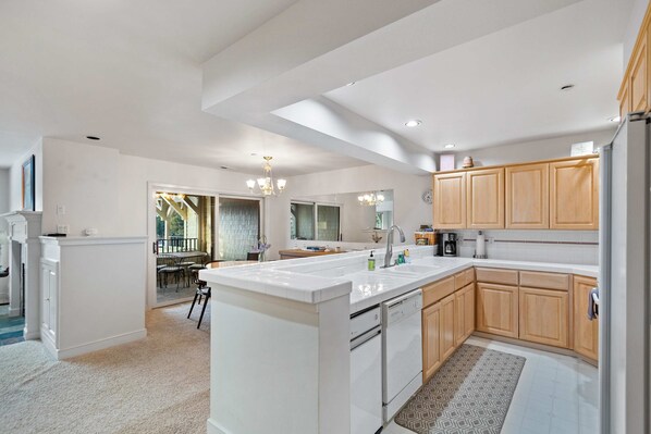 A modern kitchen with white cabinetry, a large island, and a dining area with natural light.