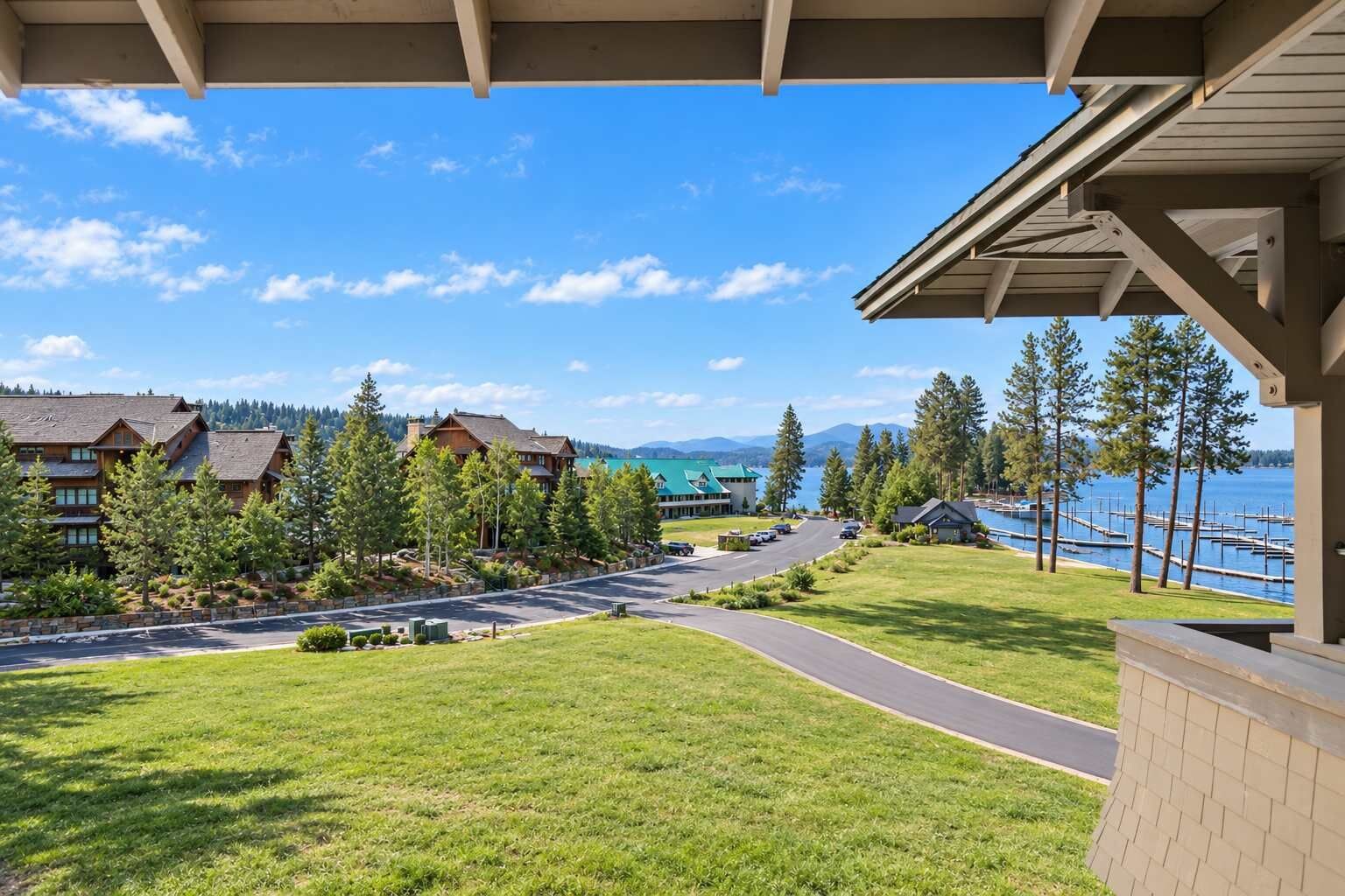 A residential area with a paved road, green lawns, and a view of a body of water with docks.