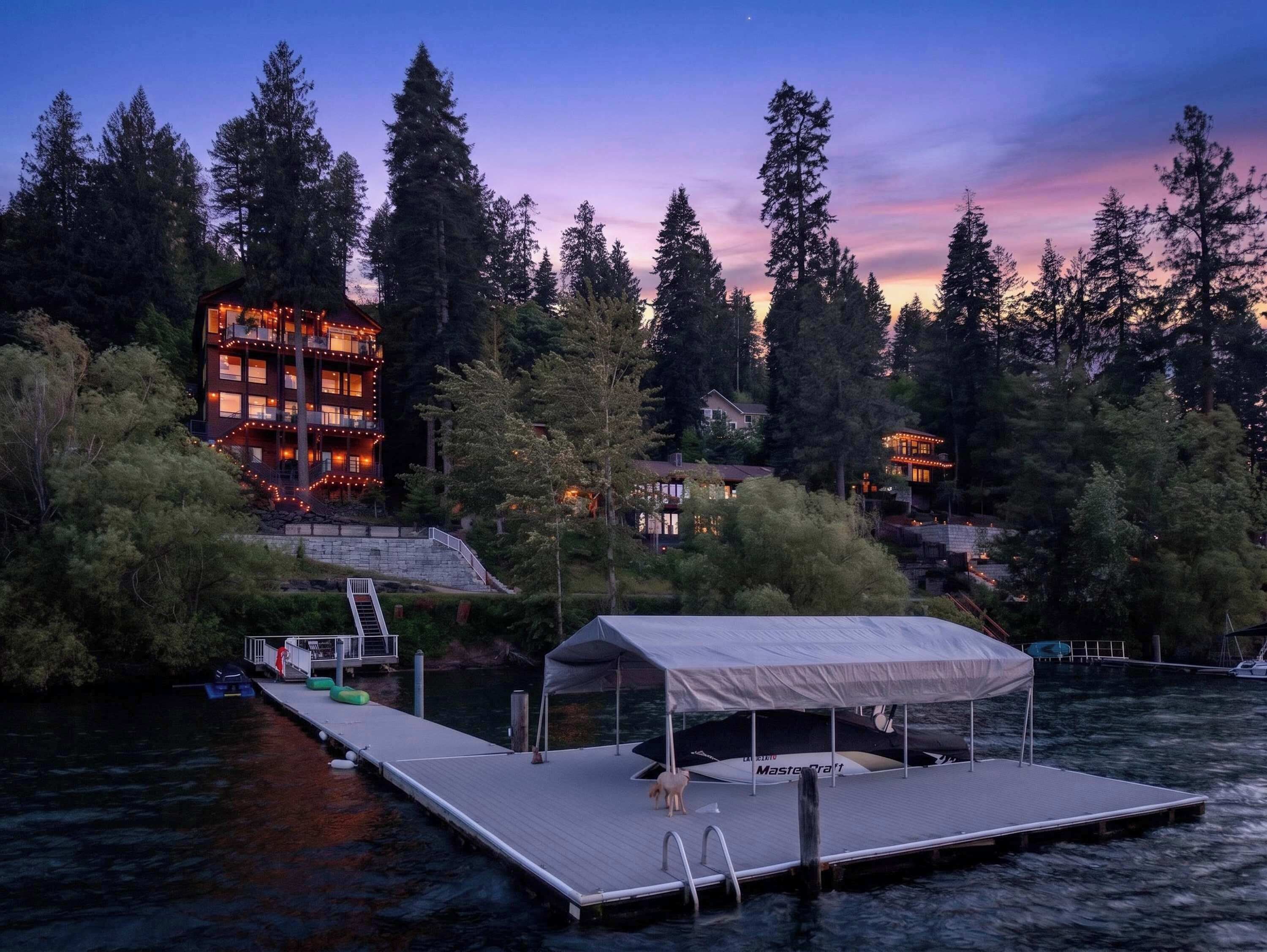 A waterfront property with a dock, a covered seating area, and a multi-story building with balconies.