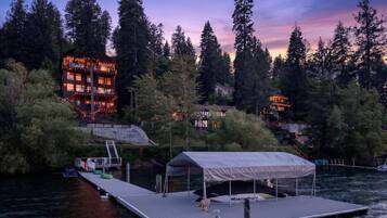 A waterfront property with a dock, a covered seating area, and a multi-story building with balconies.