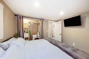 Une chambre d’hôtel avec un lit, un téléviseur fixé au mur et une salle de bain visible à travers une porte ouverte.
