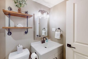 Une salle de bain avec un lavabo blanc, un miroir, des toilettes et un porte-serviettes.