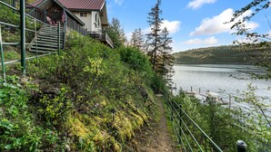A cabin with a metal roof, a staircase leading up to a porch, and a view of a lake.