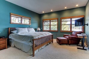 Un dormitorio con cama, dos ventanas, un escritorio y una silla.