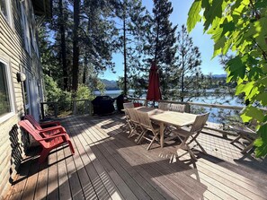 A wooden deck with a table and chairs, a barbecue grill, and a view of a lake. - Lake House w/ Private Dock & Decks, 4BR/3BA (Hayden)