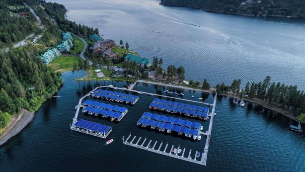 Vue aérienne d’une propriété au bord du lac, comprenant un port de plaisance, plusieurs bâtiments dotés de toits végétalisés et un quai avec des bateaux.