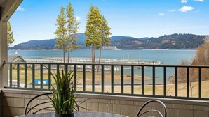 Un balcon offrant une vue sur un lac, des arbres et une côte lointaine.