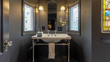 Une salle de bain avec un lavabo blanc, deux miroirs et un carrelage à motifs.