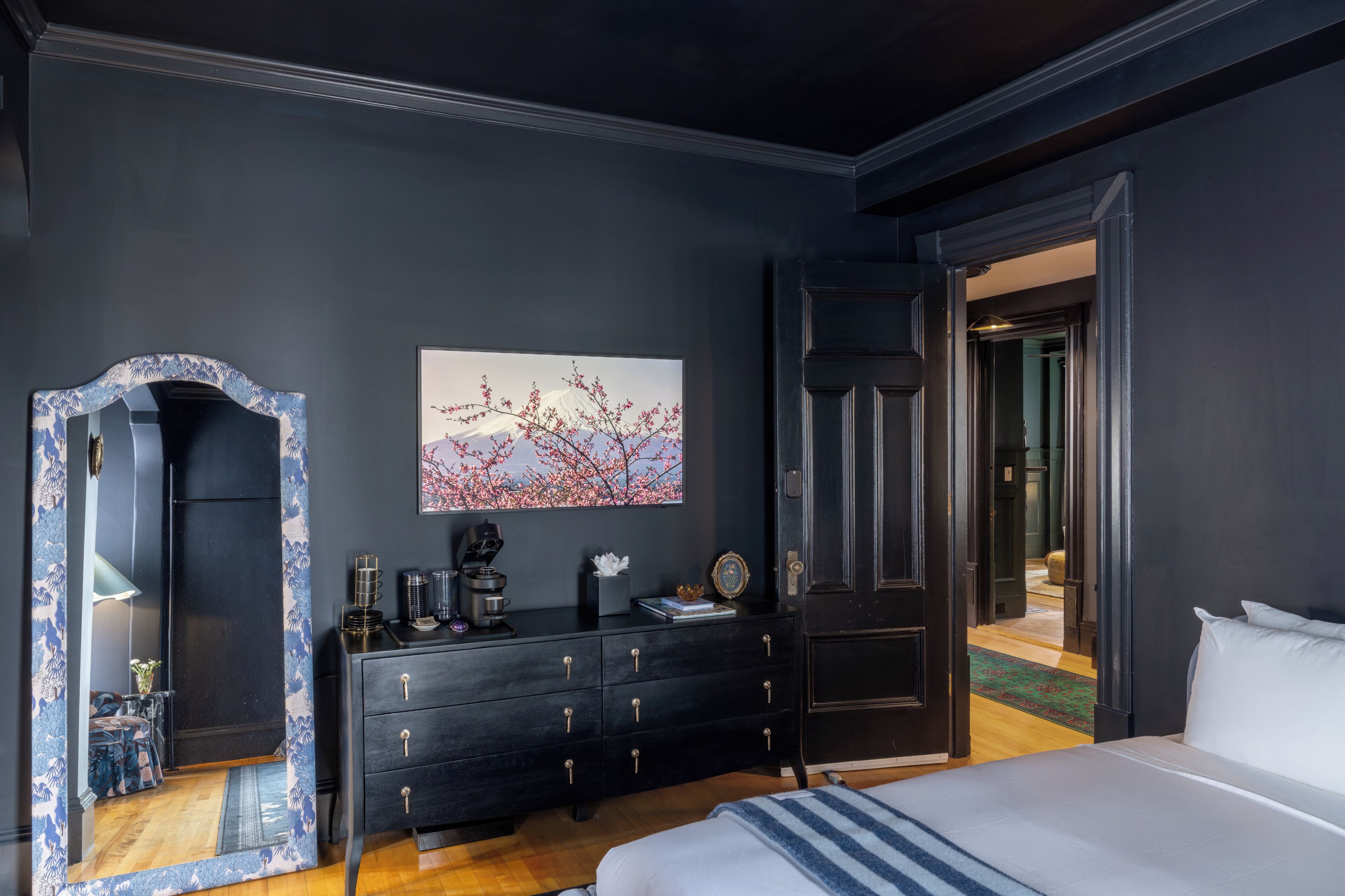 Un dormitorio con cama, cómoda, espejo y un cuadro en la pared.