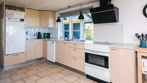 A modern kitchen with a refrigerator, microwave, coffee maker, sink, stove, and wooden cabinets. - 4 Star Holiday Home in Hejls (Hejls)